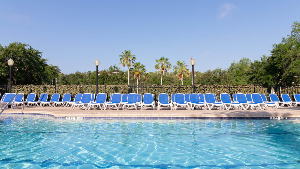a pool with blue chairs and trees
