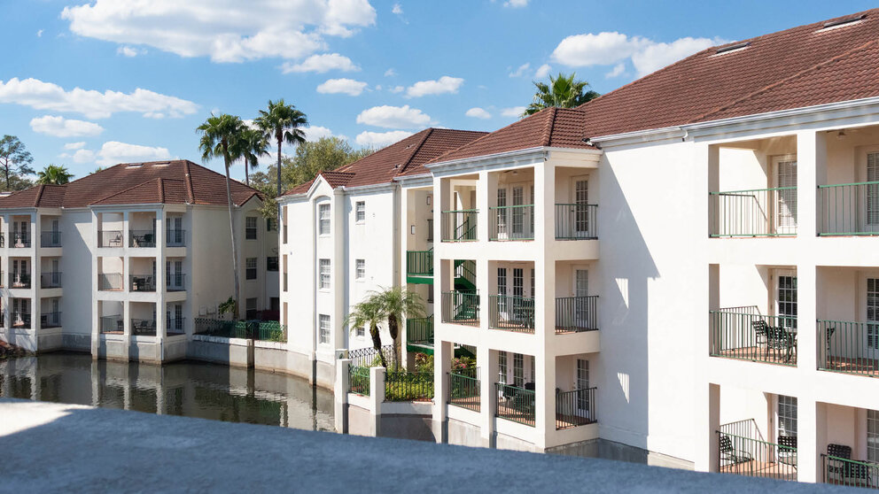 a white building with balconies and a body of water