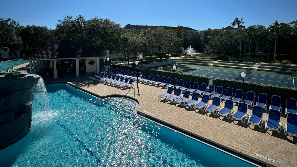 a pool with chairs and tennis court