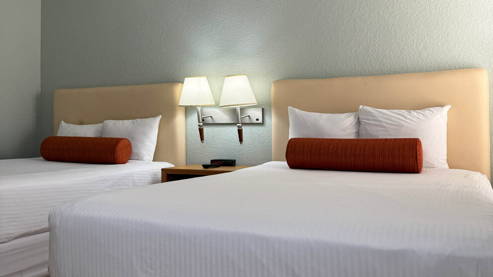 two beds with white sheets and red pillows